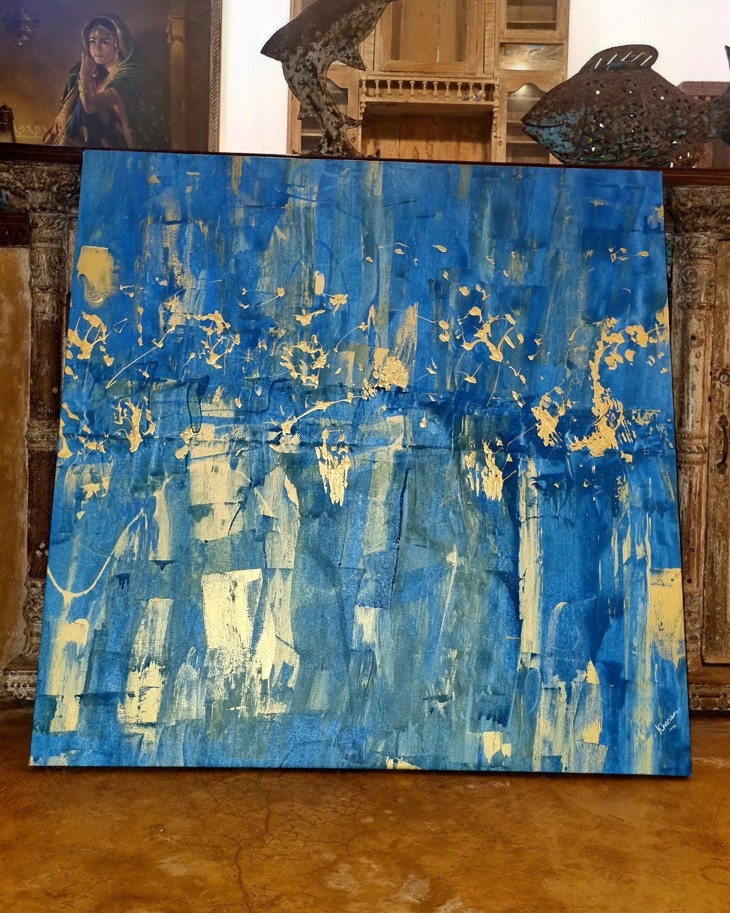 Abstract blue and gold painting on a textured wall