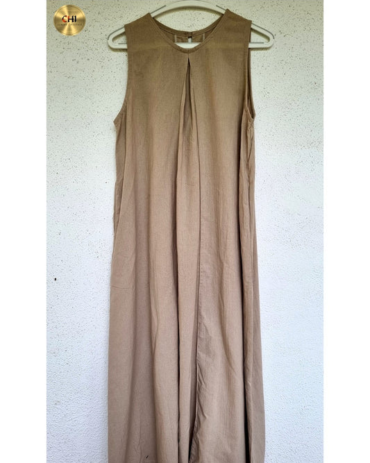 Beige sleeveless dress on a hanger against a white wall