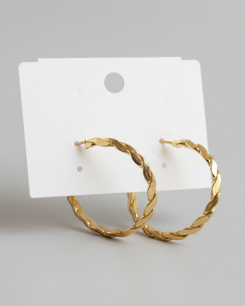 Gold hoop earrings on a white card with a beige fabric background