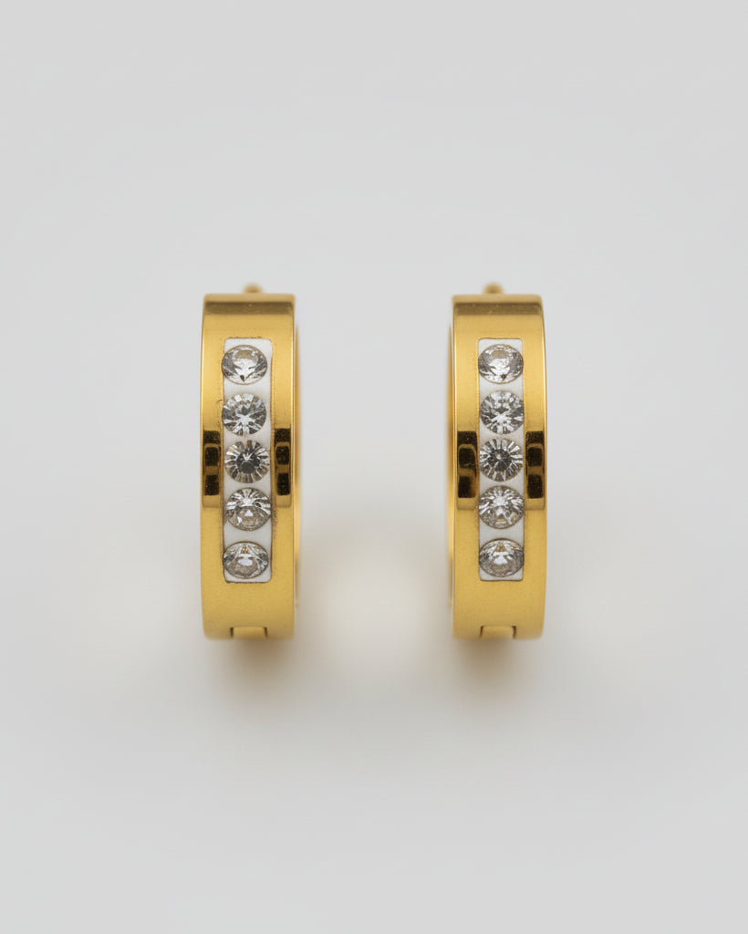 Gold hoop earring with embedded stones on a textured surface