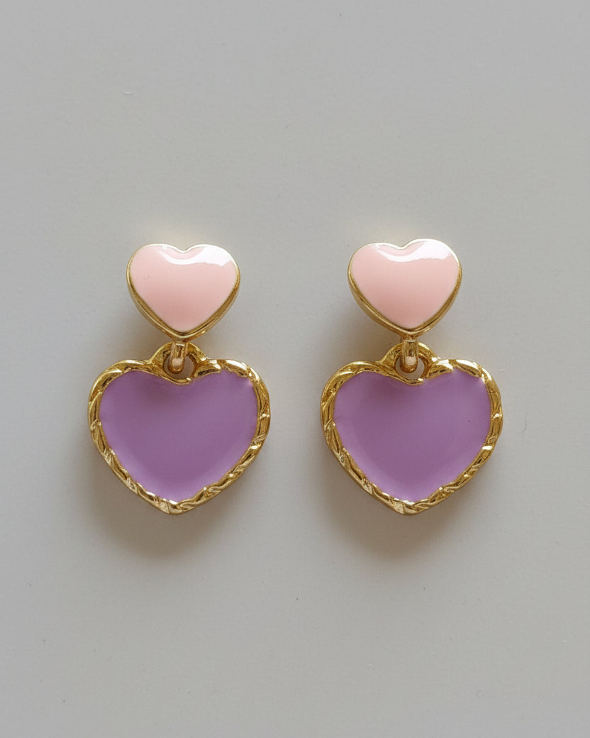 Heart-shaped earrings with pink hearts and gold frames on a beige background
