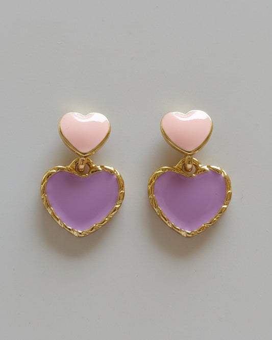 Heart-shaped earrings with pink hearts and gold frames on a beige background