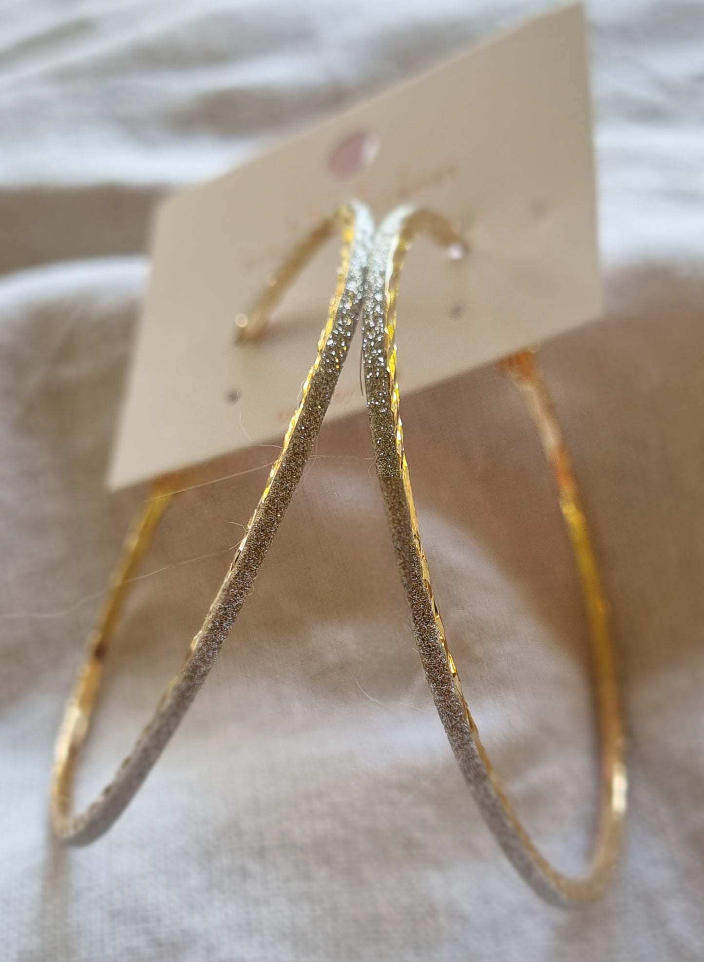 Gold hoop earrings on a white card with a white background