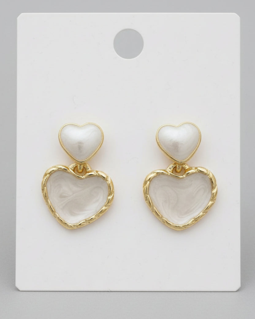 Heart-shaped earrings with gold accents on a white card.