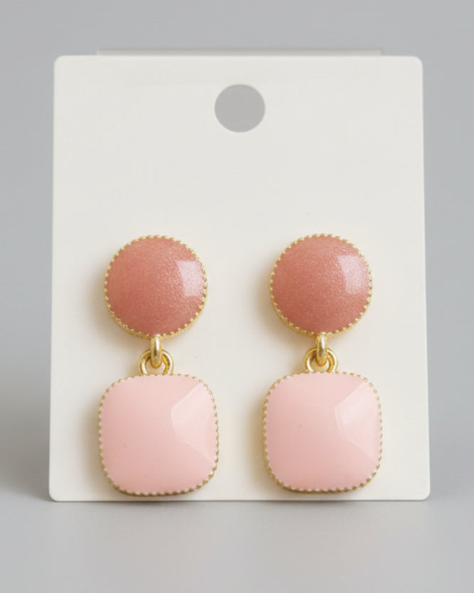 Pair of pink earrings with gold accents on a beige card.