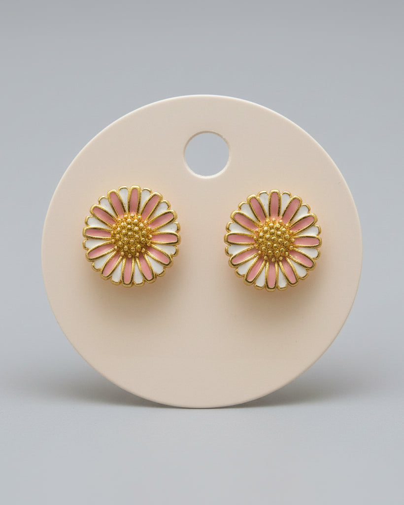 Gold and pink flower-shaped earrings on a beige display card.