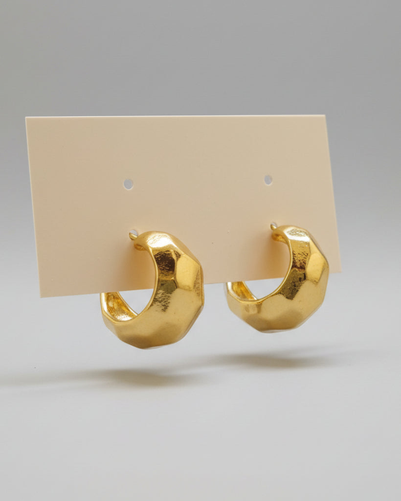 Gold hoop earrings on a beige background