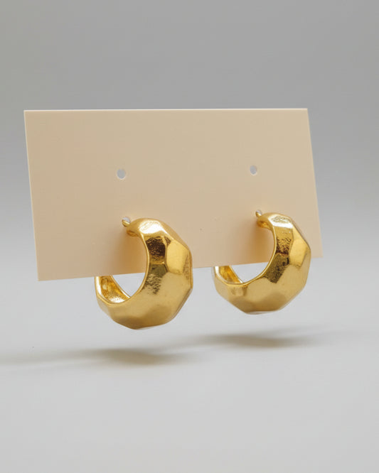 Gold hoop earrings on a beige background