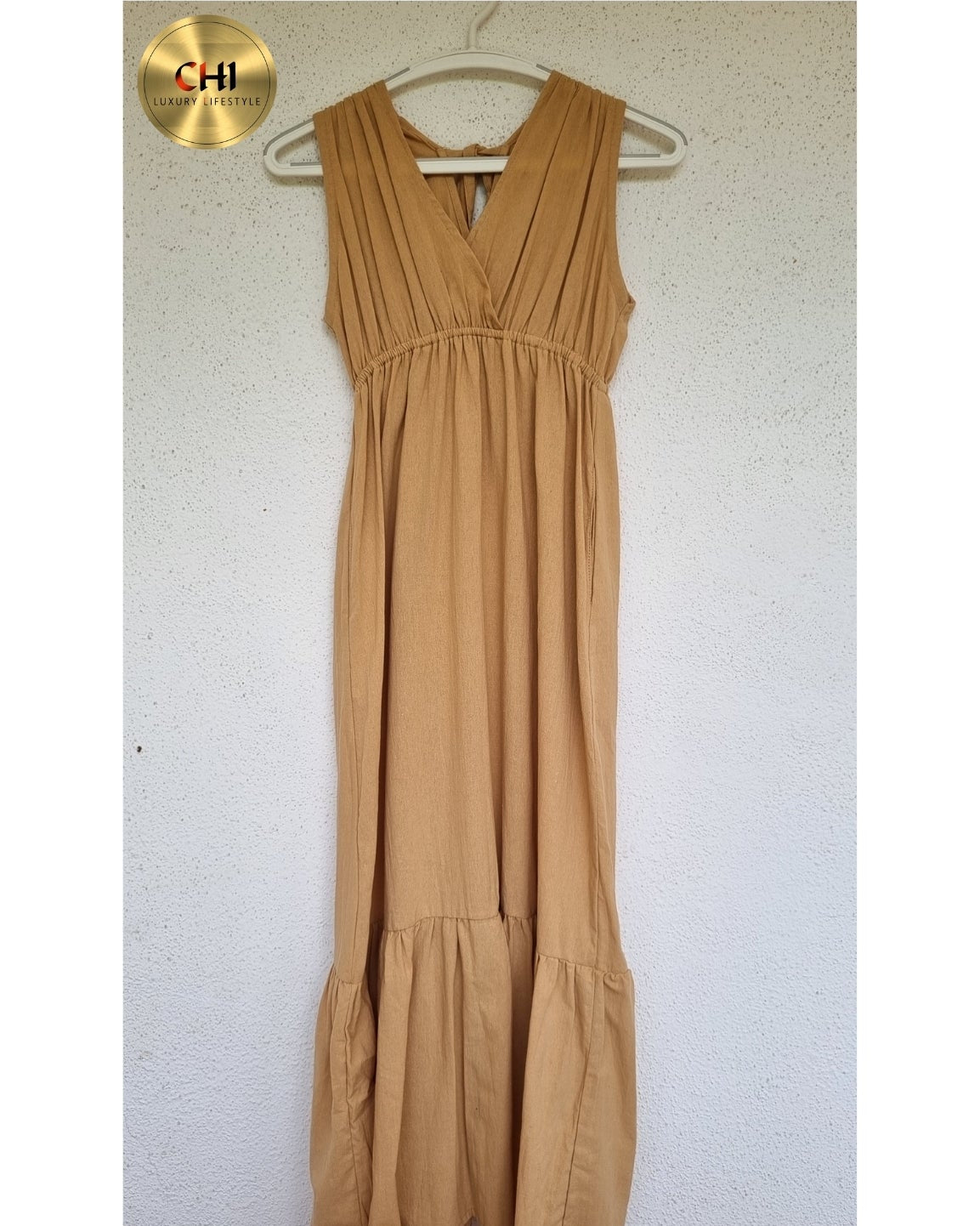 Beige dress on a hanger against a white wall with a visible brand logo.