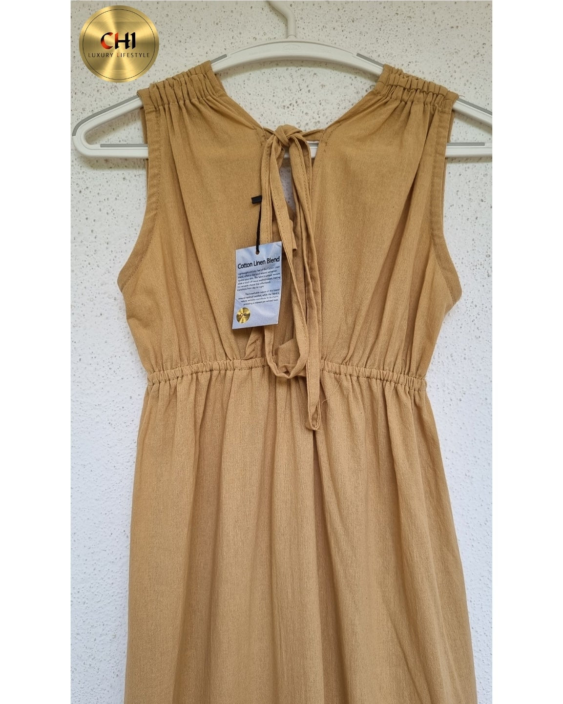 Beige dress on a hanger with a visible brand tag against a white background
