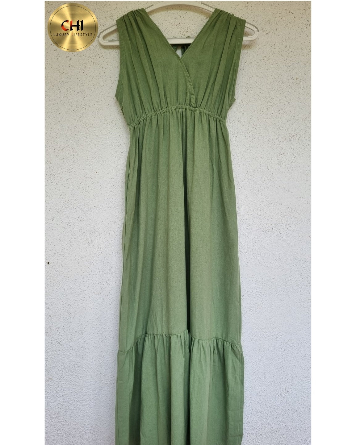 Green dress hanging on a white wall with a gold 'CHI' logo.