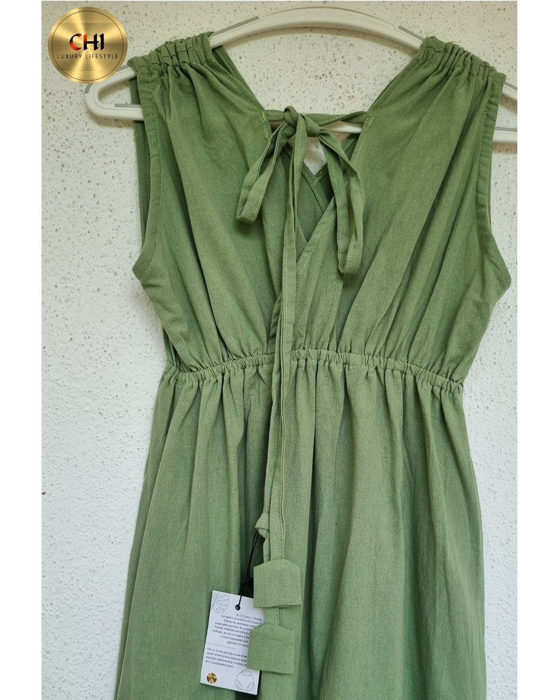 Green dress on a hanger against a white wall with a visible brand tag.