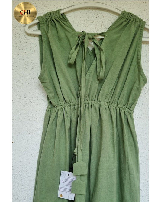 Green dress on a hanger against a white wall with a visible brand tag.