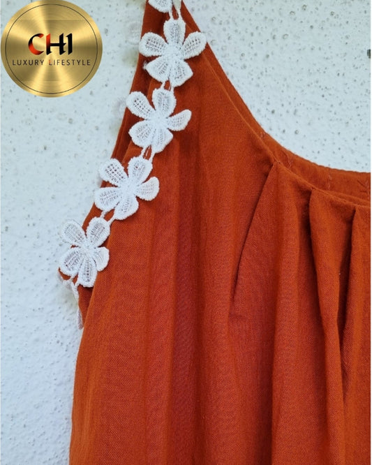 Orange dress with white floral embellishments on a textured white background