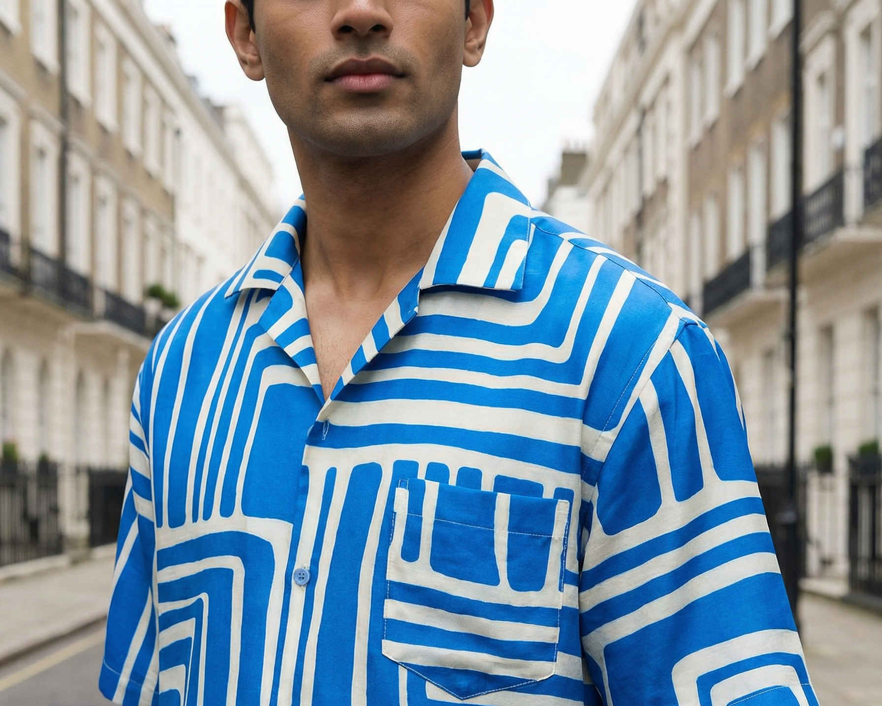 Man wearing a blue and white patterned shirt on a street.