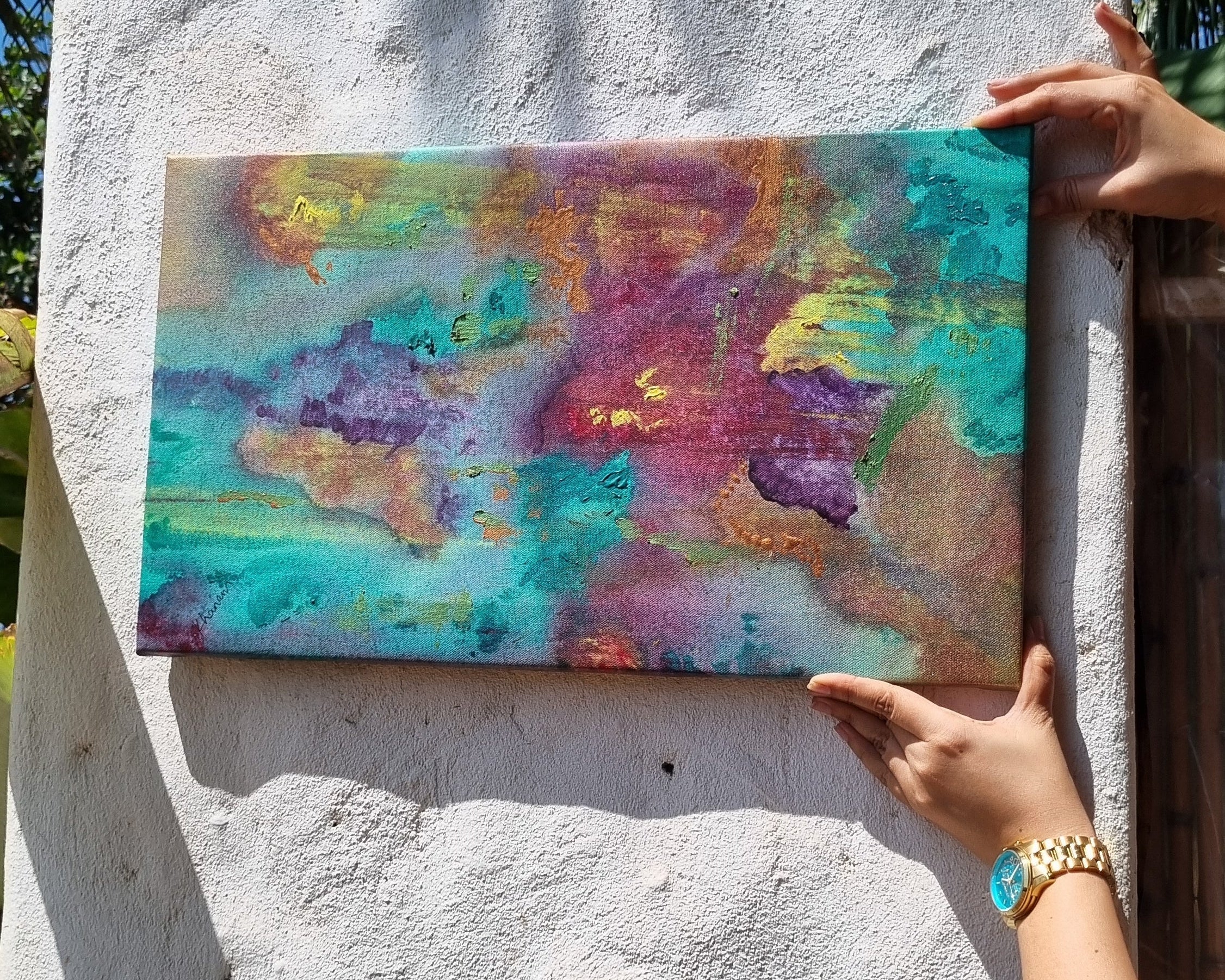Person holding a colorful abstract painting on a textured white surface